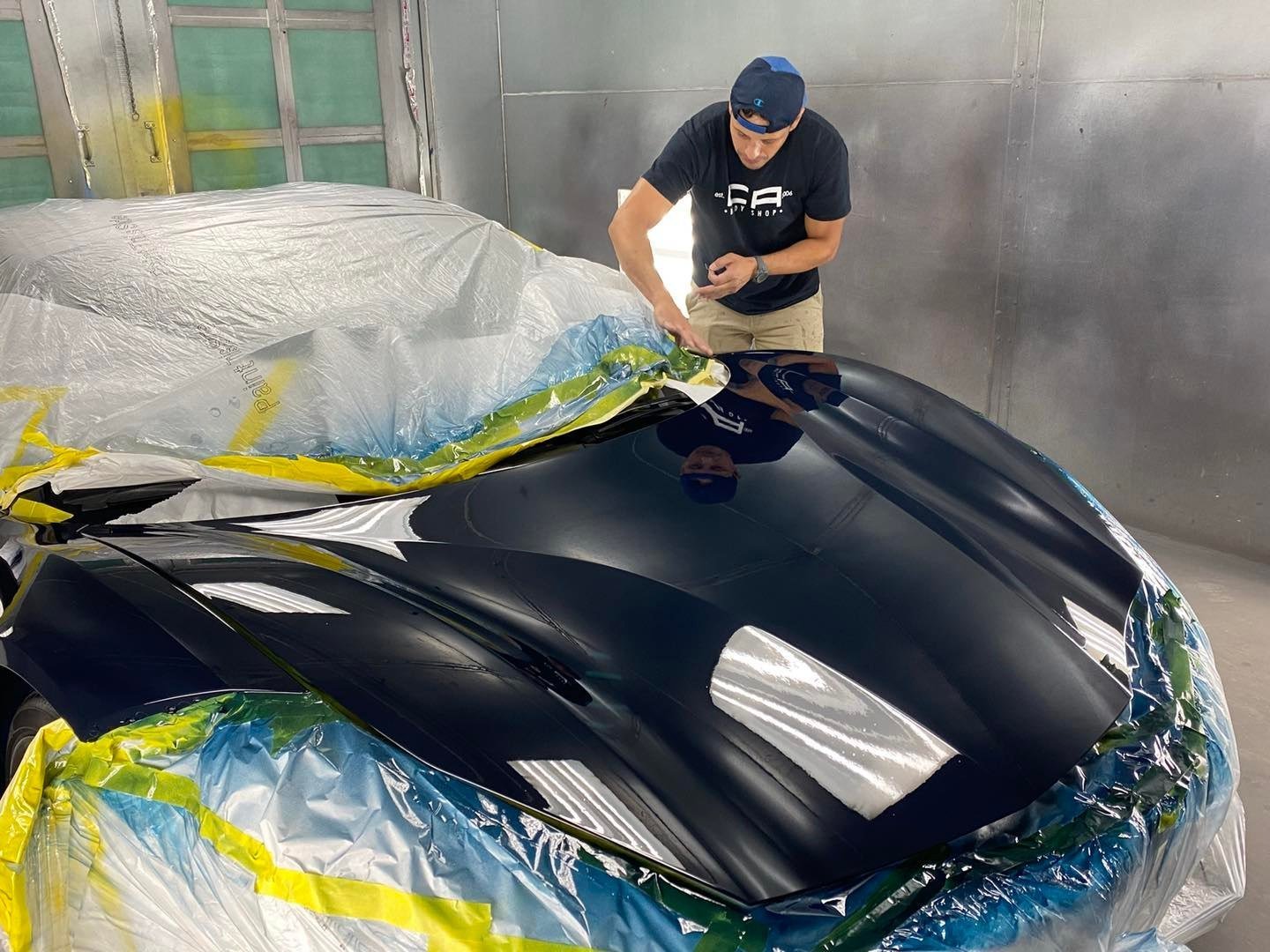 A CA Body Shop technician working on the finish of a black Ferrari